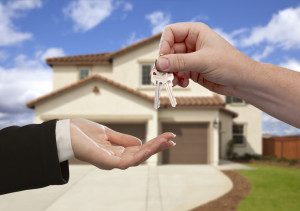 Handing Over the House Keys in Front of a Beautiful New Home.